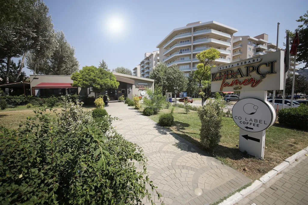 Bursa İskender nerede yenir? sorusunun cevabı: Kebapçı Tamer'in şık iç mekanında, masada servis edilmiş, lezzetli bir Bursa İskender Kebabı tabağı.