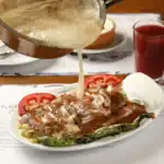 Kebapçı Tamer'de, üzerine özel tereyağı gezdirilen, dumanı tüten 1.5 porsiyon Bursa döner kebabı tabağı.