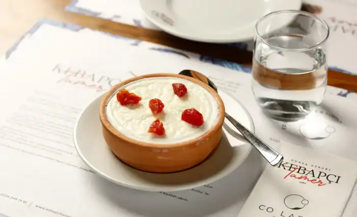 Kebapçı Tamer'in özel üretim manda yoğurdu, üzerinde Bodrum'dan gelen güneşte kurutulmuş kiraz domatesler ile servis ediliyor.